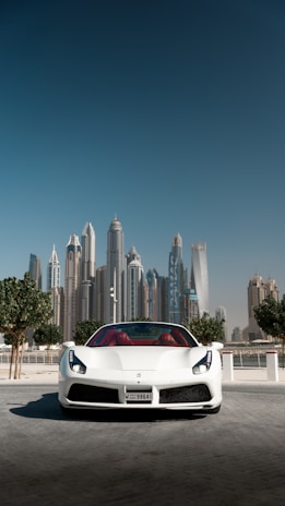 White sports car gleaming under a bright Middle Eastern city sky.
