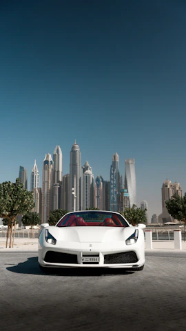 A sleek, shiny car parked in front of a modern city backdrop under a clear sky.