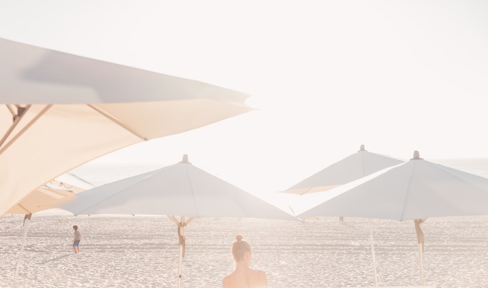 a group of white umbrellas sitting on top of a sandy beach