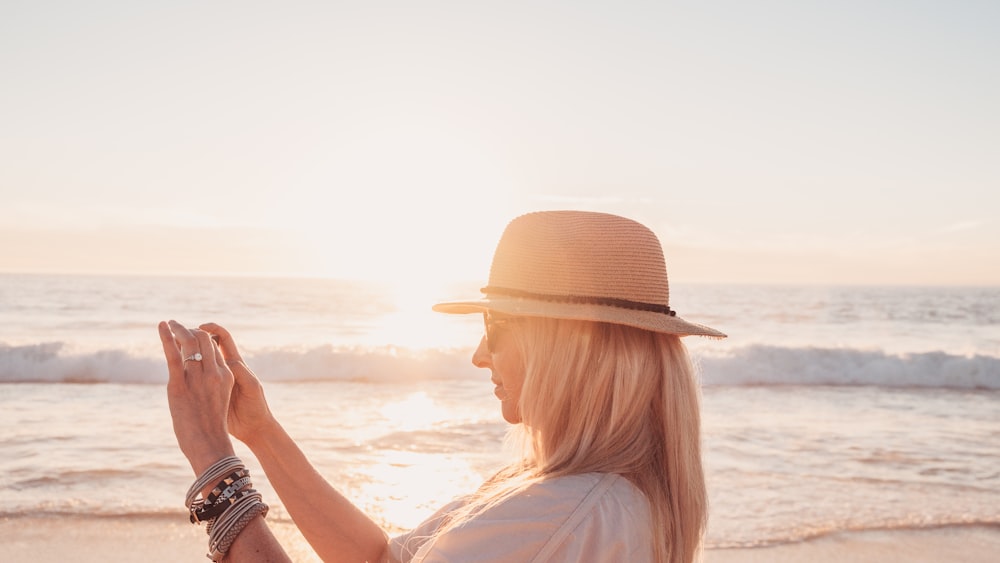 a woman in a hat standing on a beach