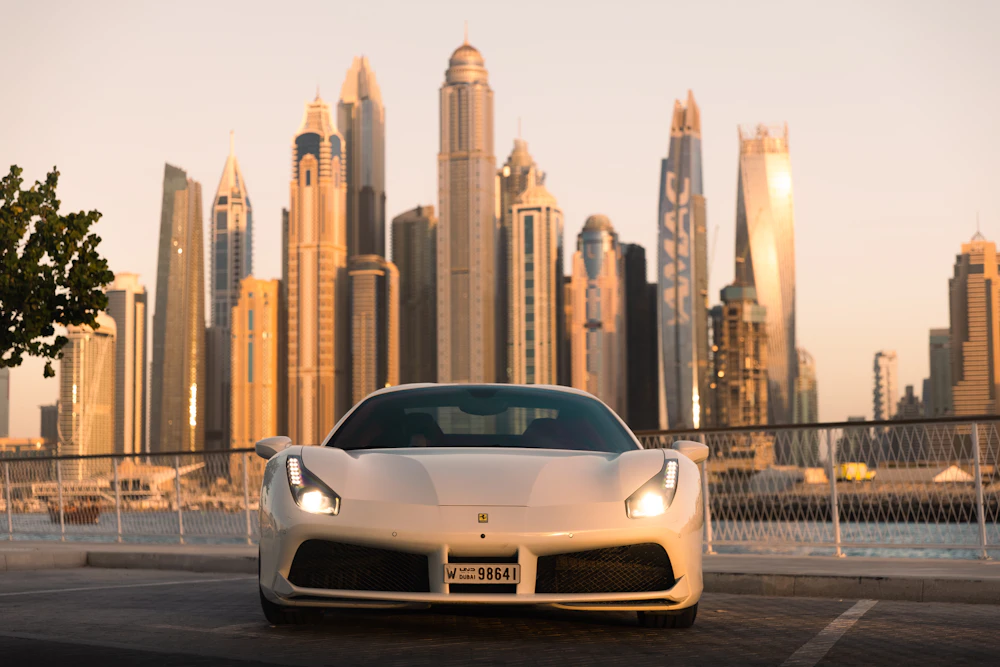 White Ferrari 488 with Dubai plate in front of the Dubai Marina skyline