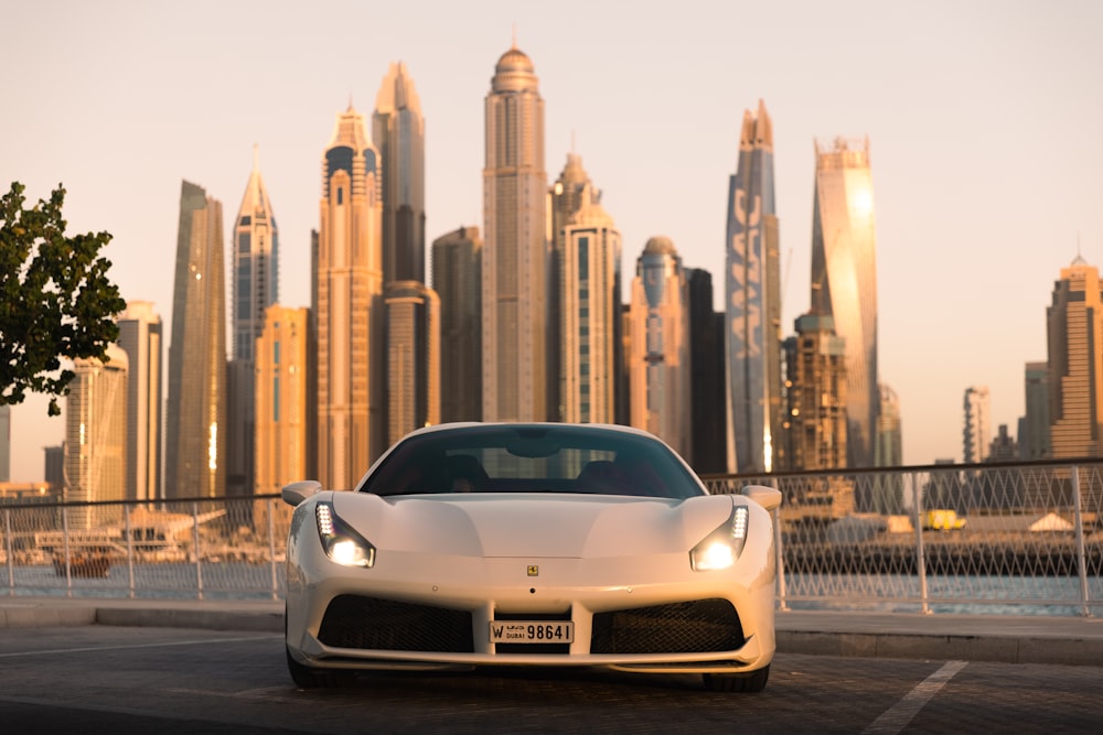 Un auto deportivo blanco estacionado frente al horizonte de una ciudad