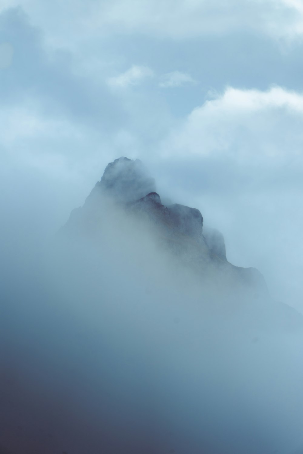 a mountain covered in fog and clouds on a cloudy day