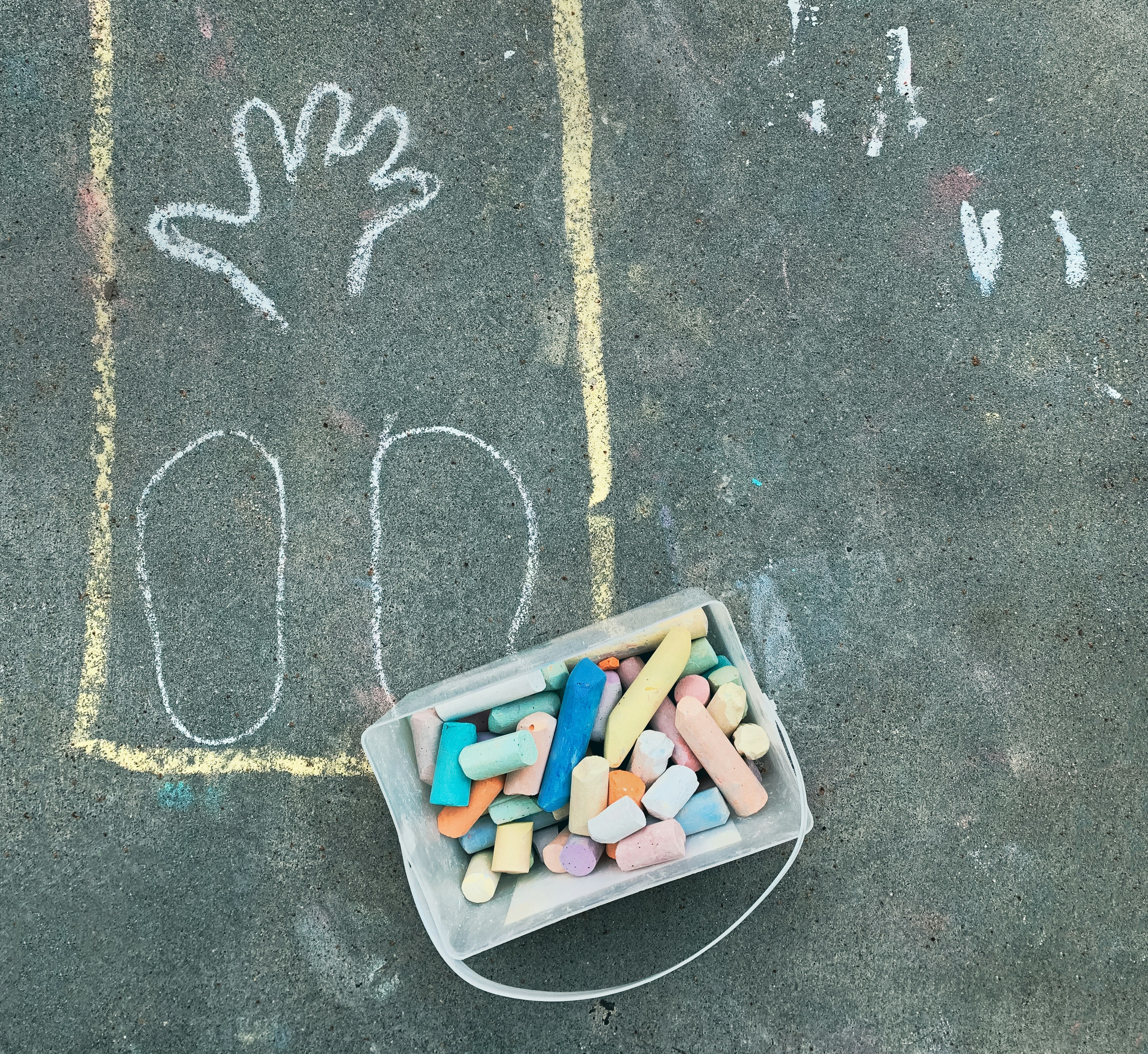 a chalk drawing of a hand and a bucket of colored crayons