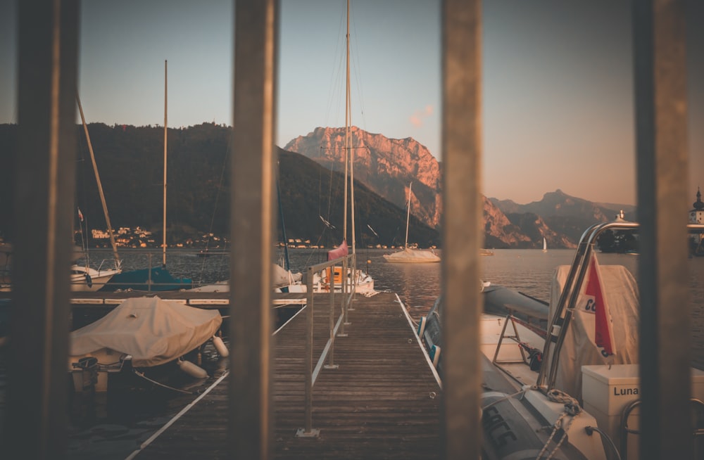 a view of a dock with boats in the water and mountains in the background