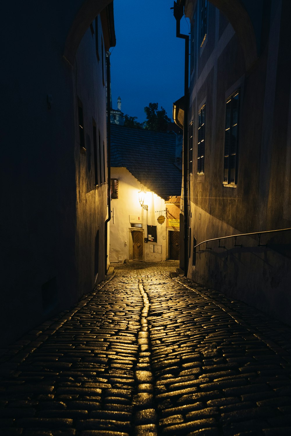 a cobblestone street at night with a light on