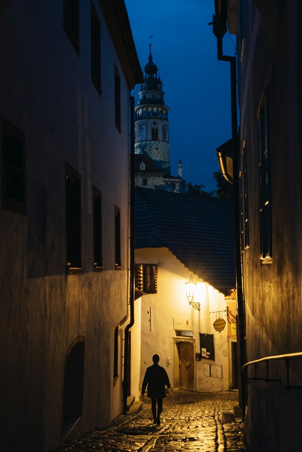 a man walking down a cobblestone street at night