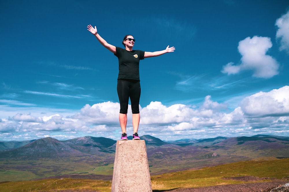 a woman standing on top of a stone pillar