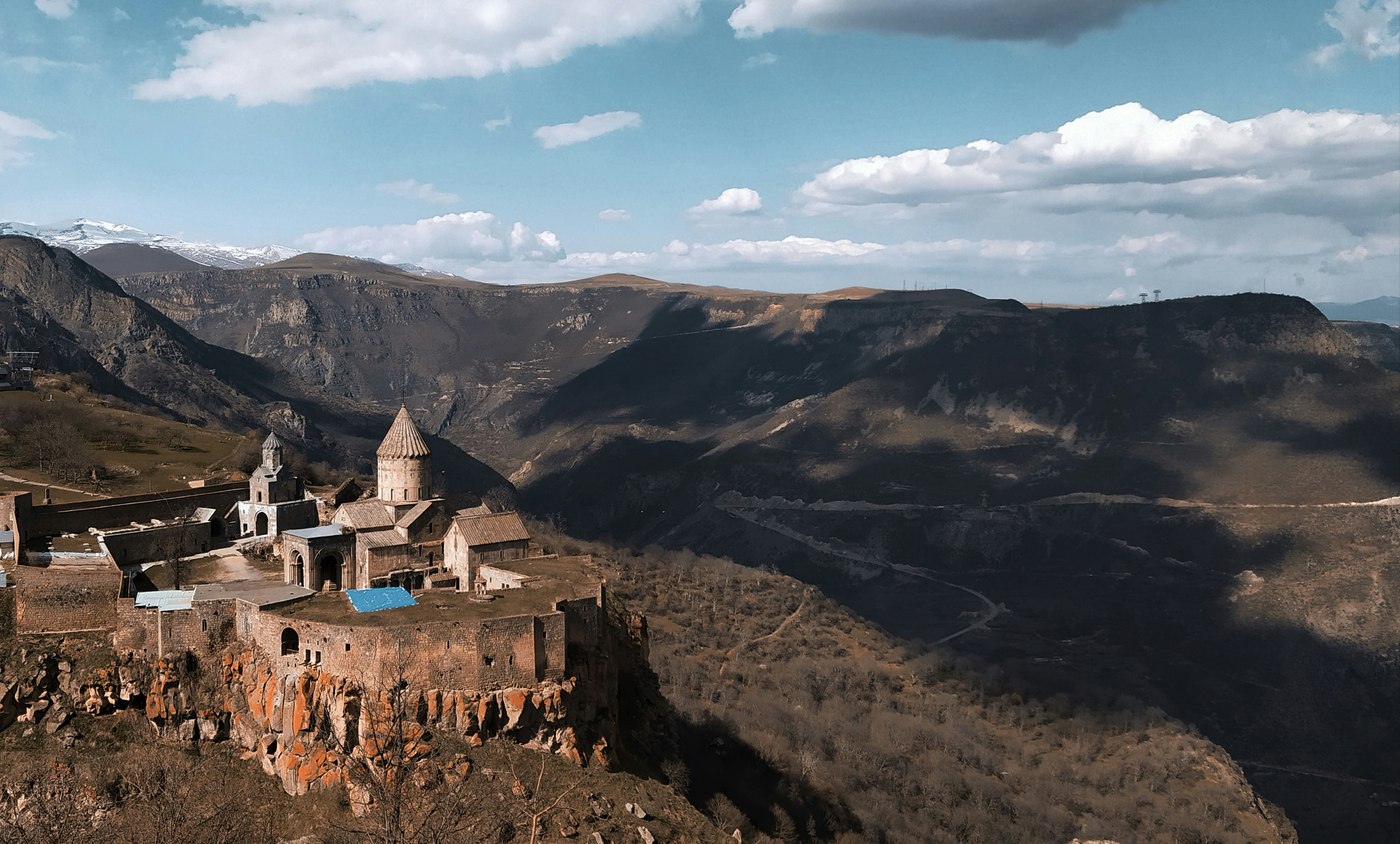 a castle perched on top of a mountain surrounded by mountains, Beautiful view of the Tatev Monastery and mountains in Tatev, Syunik, Armenia