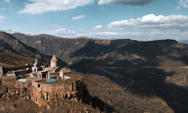 A castle perched on top of a mountain surrounded by mountains — Tatev, Armenia