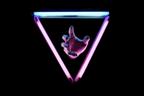 a person's hand pointing towards a triangle shaped object