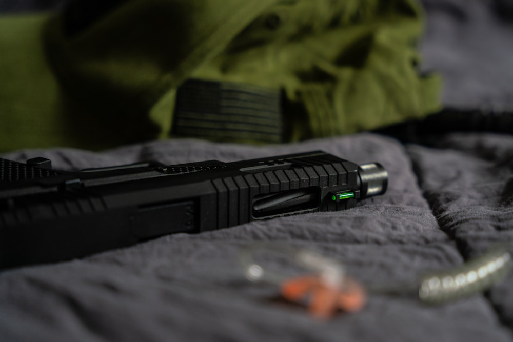 a gun laying on top of a bed next to a pair of scissors