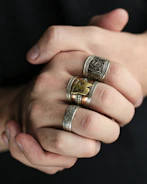Stacked rings in mixed metals shown on a youthful hand with modern street style nails.