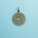 A bronze-colored pendant with intricate mandala patterns and an Om symbol in the center rests on a light blue background.