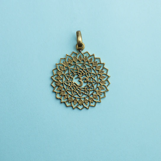 Elegant brass yantra pendant resting on a textured wooden surface
