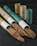 A collection of incense sticks partially pulled out of cylindrical cardboard containers, with more containers standing upright in the background on a dark wooden surface.