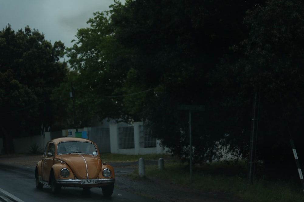 an old car driving down the road in the rain
