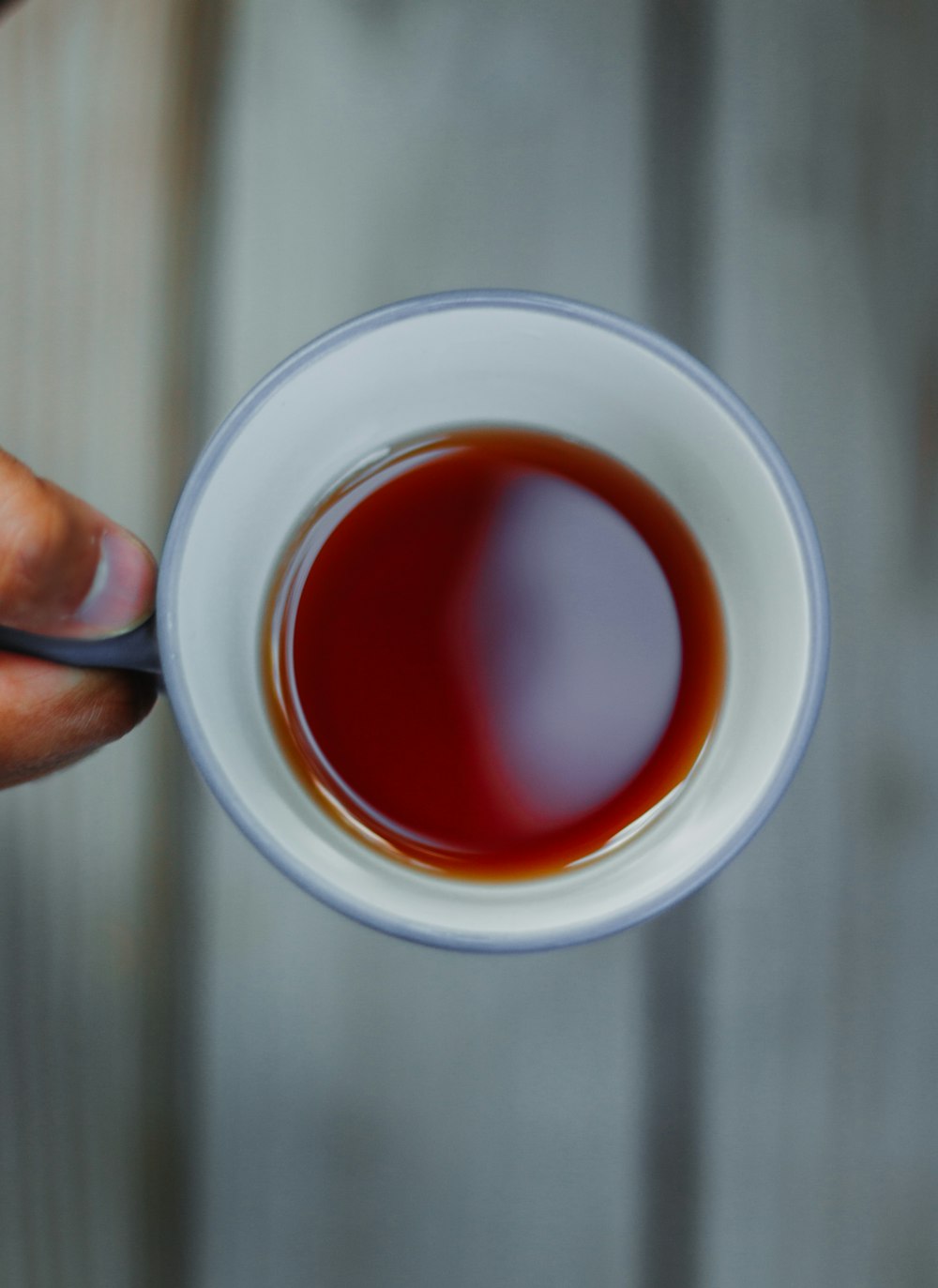 a person holding a cup of tea with a spoon