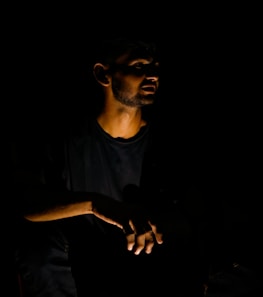 a man sitting in the dark holding a cell phone