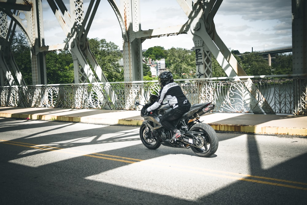 a man riding a motorcycle across a bridge