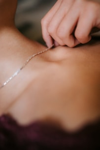 Close-up of hands inspecting a delicate imitation necklace under bright light.