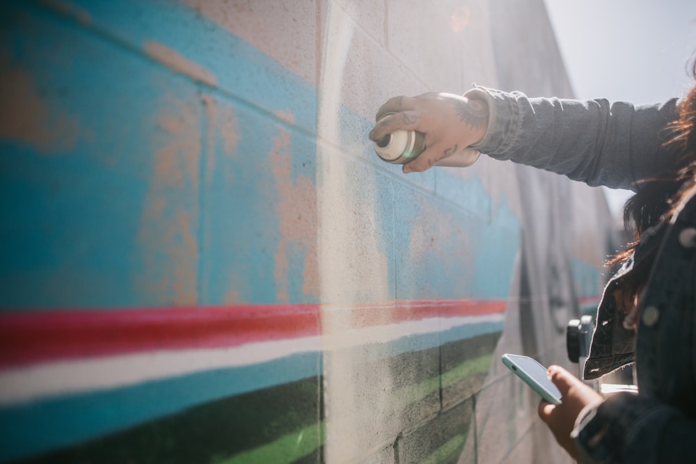 a woman using a cell phone to paint a wall
