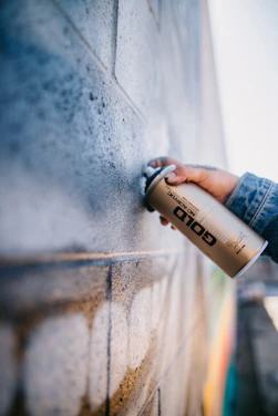 A skilled painter applying a smooth, rich gold finish on a modern black exterior wall.