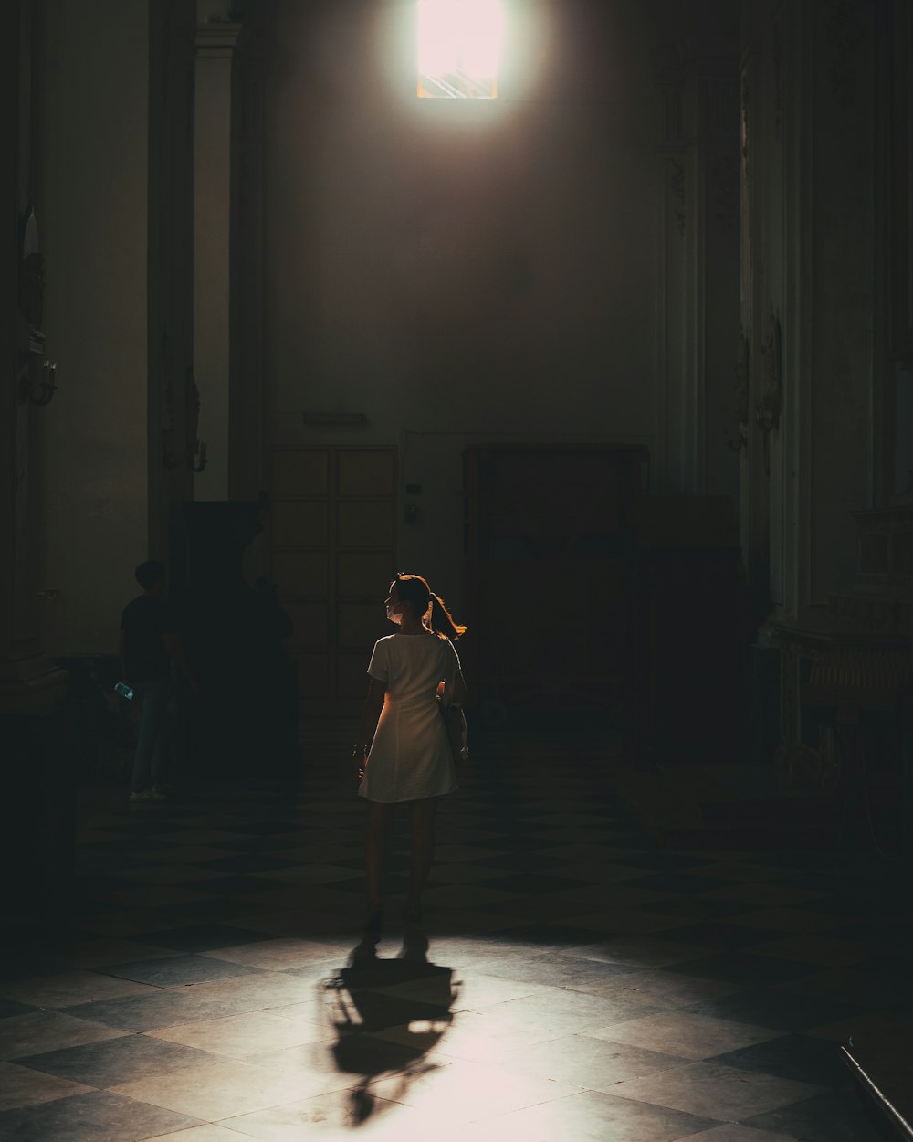 a woman standing in a dark room with a light shining on her