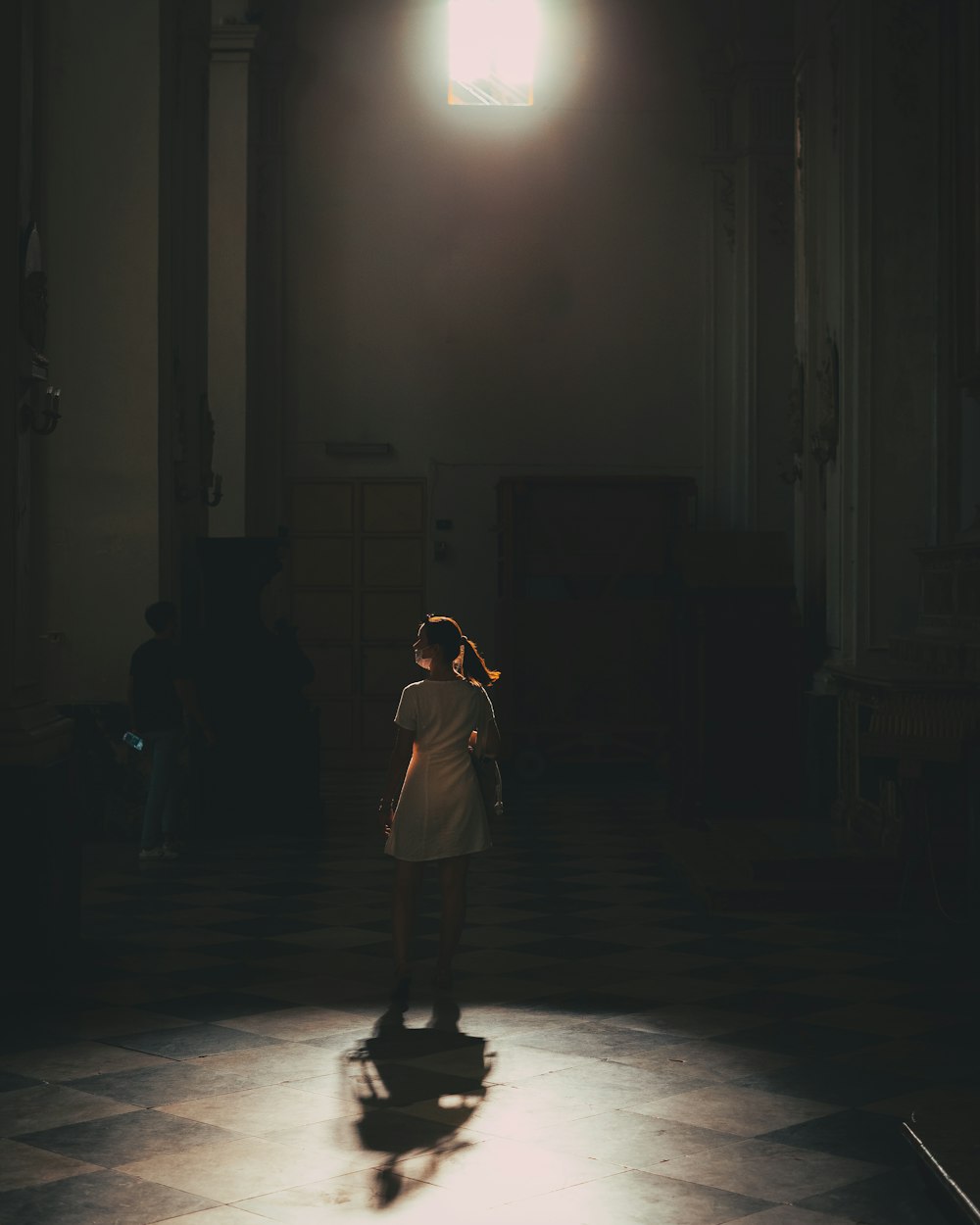 Una mujer parada en una habitación oscura con una luz brillando sobre ella