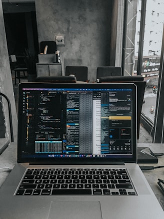 A high-performance laptop open on a clean workspace with code on the screen.