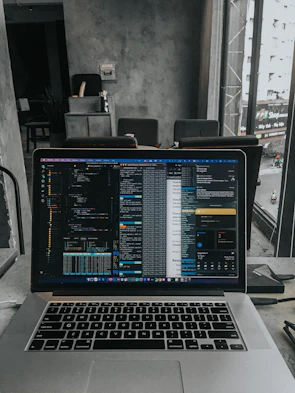 A modern laptop open with colorful code on the screen in a cozy workspace.