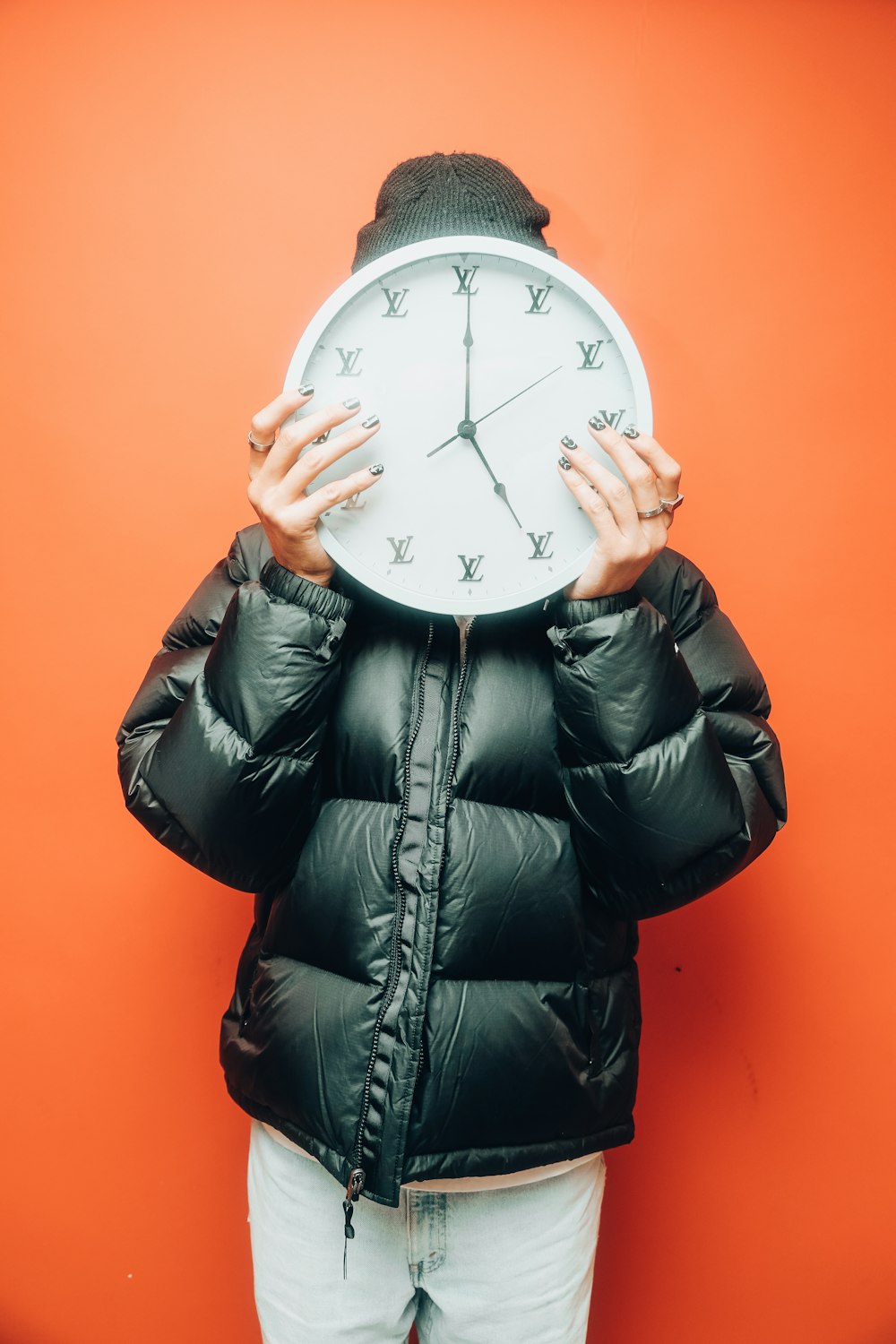 a woman covering her face with a clock