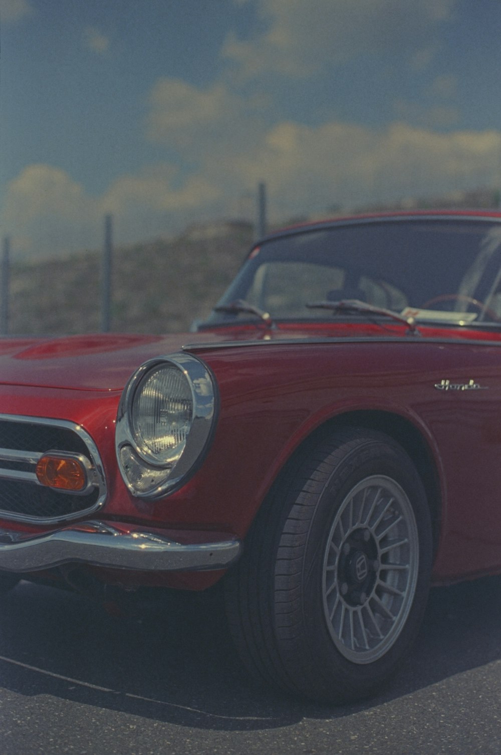 a red classic car parked in a parking lot