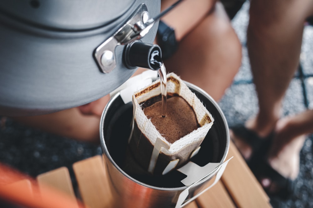 a person pours a cup of coffee into a pot