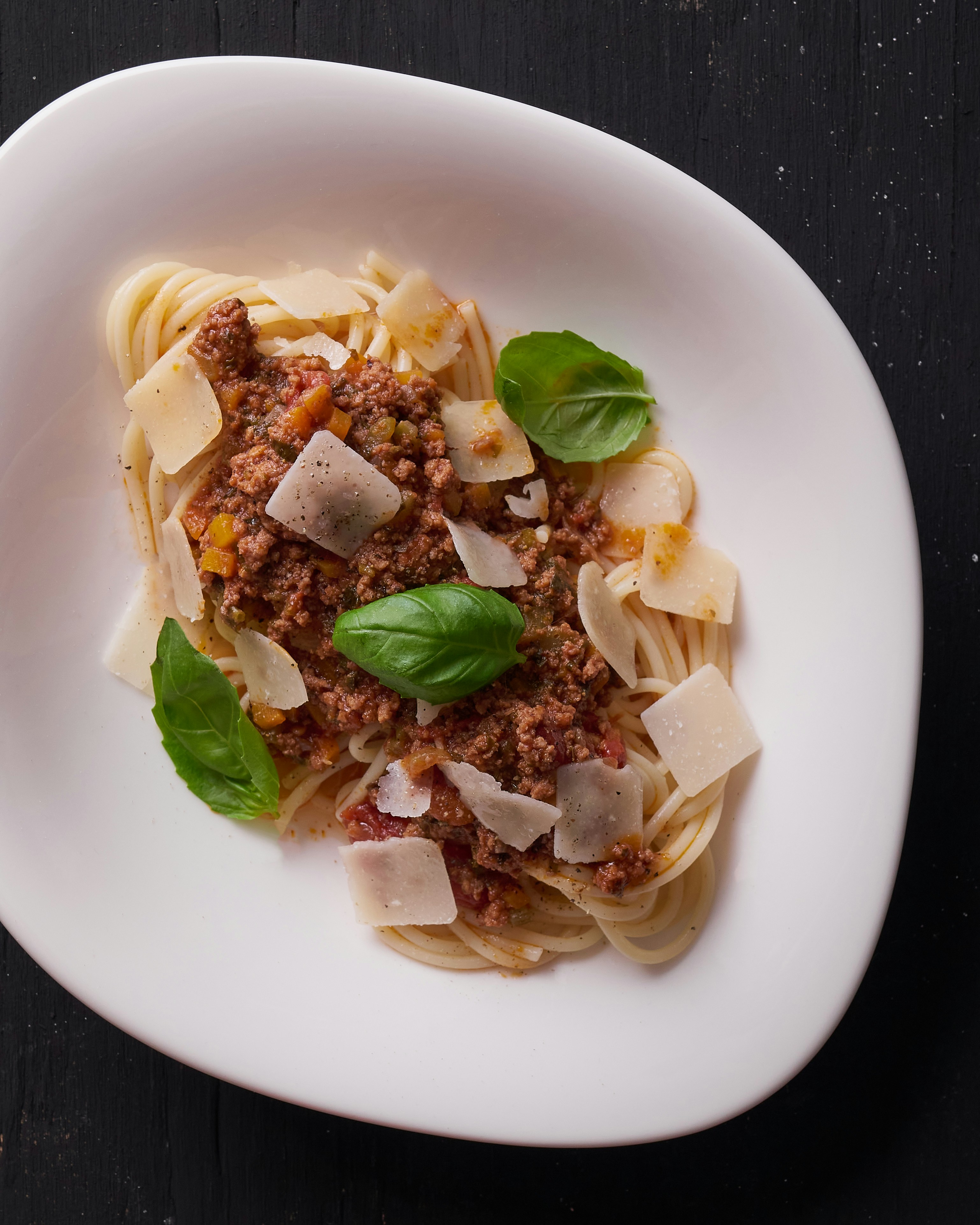 Spaghetti bolognese with rich meat sauce and parmesan cheese on white plate