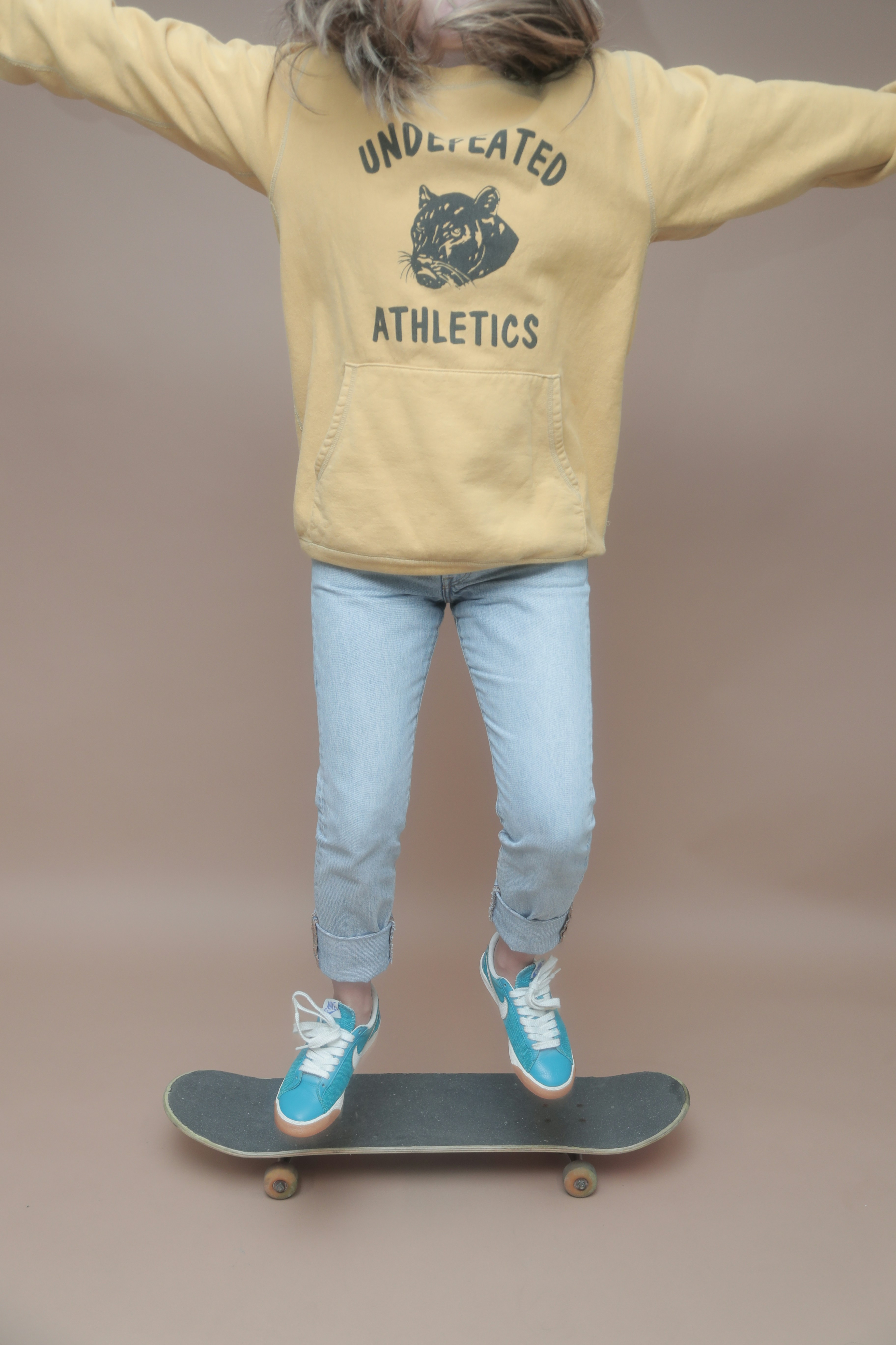 a young girl riding a skateboard with her arms outstretched