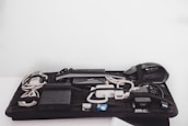 An organized grid containing various electronic accessories, including cables, a mouse, a power bank, and chargers, all secured with elastic bands.