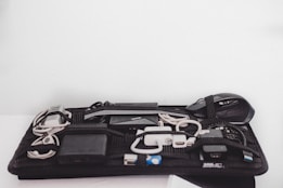 An organized grid containing various electronic accessories, including cables, a mouse, a power bank, and chargers, all secured with elastic bands.