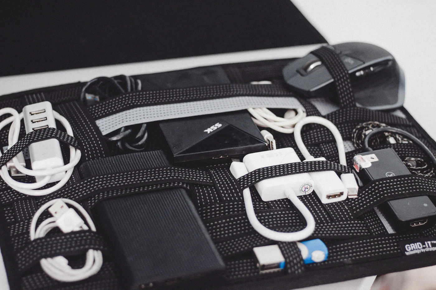 A zipped travel organiser holding coiled cables, adapters and a mouse