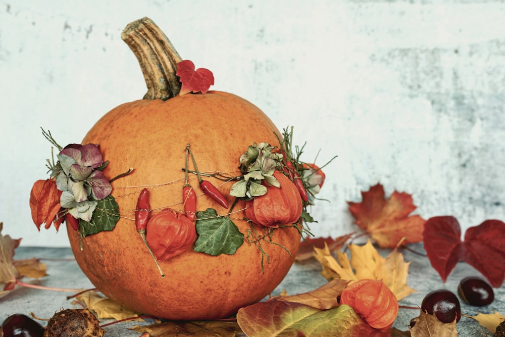 a pumpkin decorated with flowers and leaves on a table