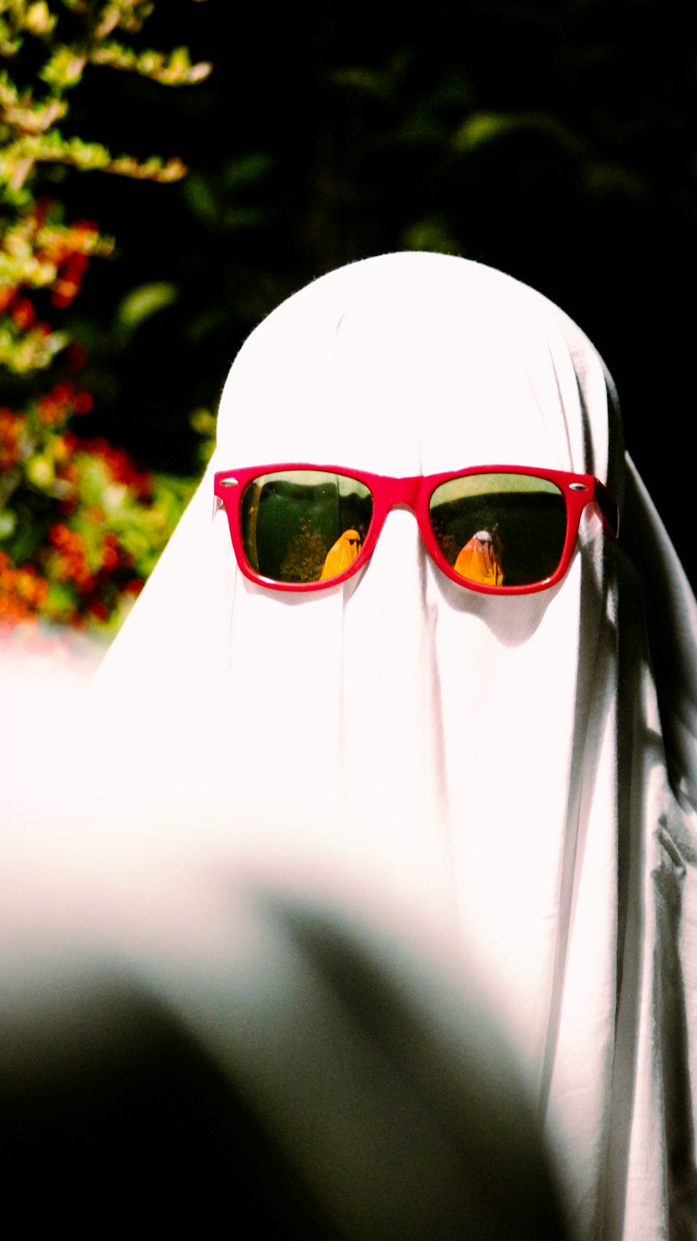 une personne portant un voile blanc et des lunettes de soleil rouges