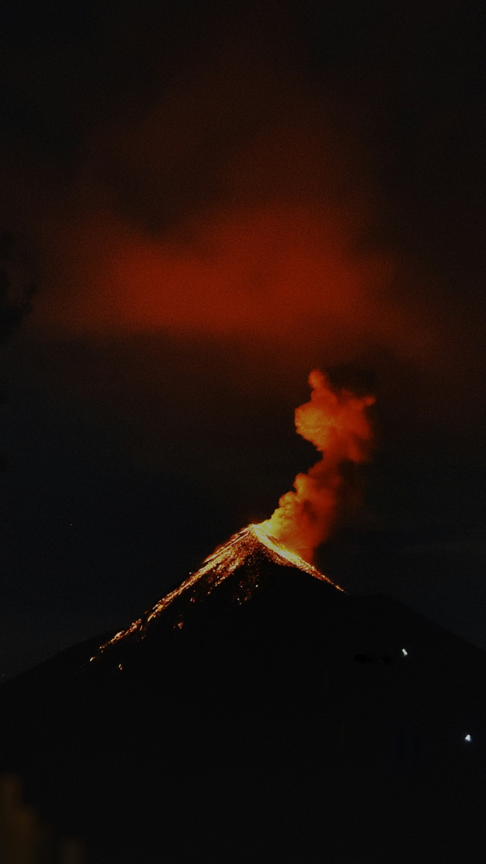 Ein Vulkan bricht Rauch aus, als er in den Nachthimmel ausbricht