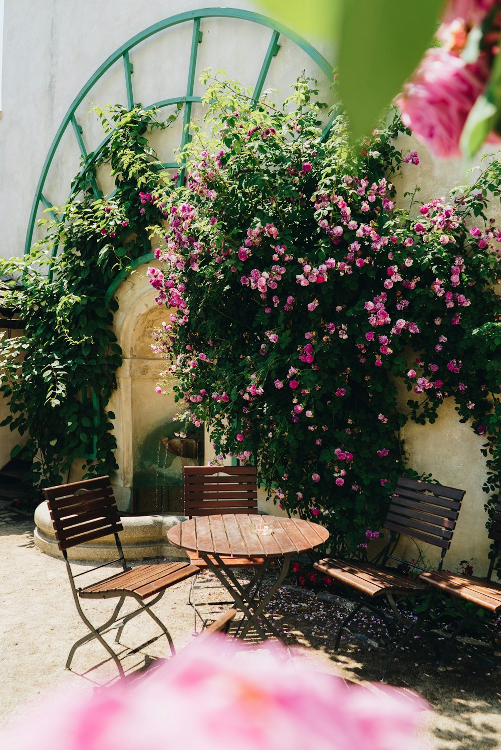 a patio with a table and chairs and flowers on the wall