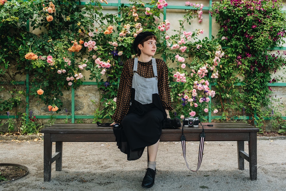 a woman sitting on a bench in front of flowers