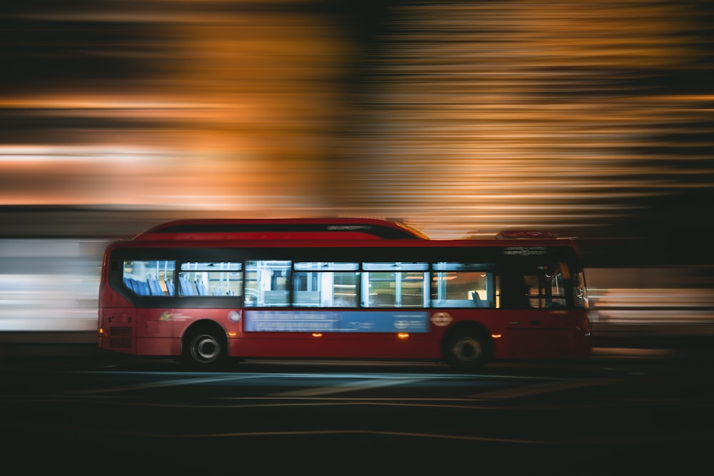 a red bus driving down a street at night