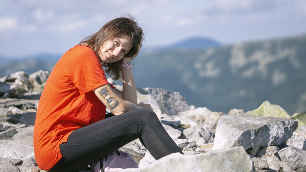 a woman sitting on top of a pile of rocks talking on a cell phone