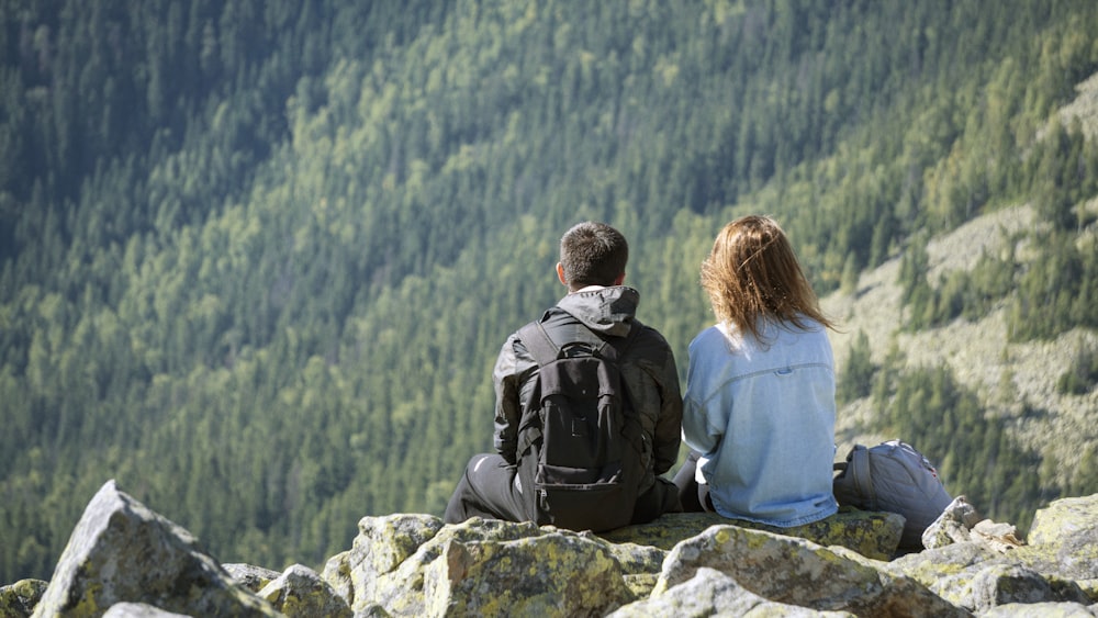 a couple of people sitting on top of a mountain