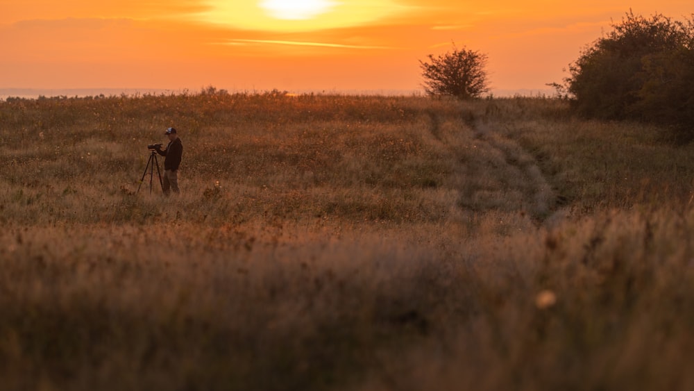a person standing in a field at sunset
