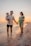 A happy family standing on the sandy shores of Portugal's Silver Coast at sunset.