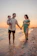 A candid photo of a smiling family wrapped in golden afternoon sunlight on a sandy beach.